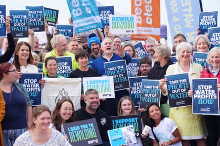Davey poses among a group of people holding placards calling for the privatisation of water companies