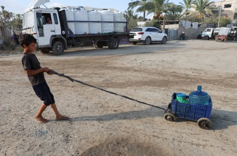 A Palestinian boy drags containers of water amid shortages at a distribution point in Deir al-Balah in the central Gaza Strip.