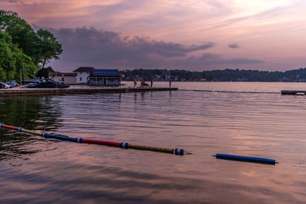 A lake with some buoys and buildings in the background