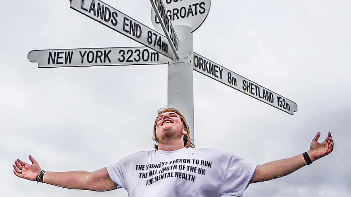 Marcus Skeet by a John o'Groats sign showing distances to Land's End, Orkney, Shetland and New York