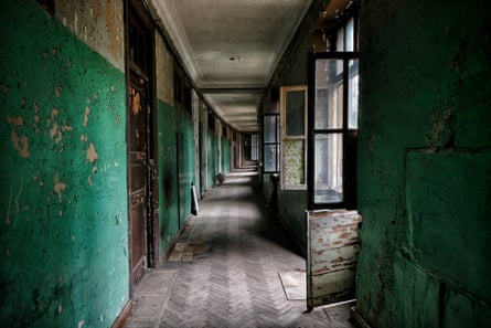 A long grand abandoned corridor with peeling paintwork