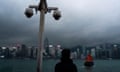 Surveillance cameras are seen as a visitor looks at Victoria Harbour in Hong Kong