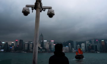 Surveillance cameras are seen as a visitor looks at Victoria Harbour in Hong Kong
