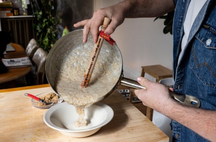 A saucepan of creamy porridge being poured into a white bowl.