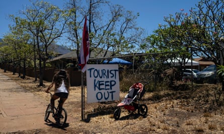 a girl riding a bike past a sign saying tourist keep out