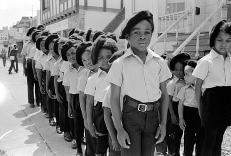 A line of young children in uniform with black berets.
