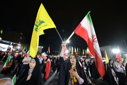 Women holding flags of Iran and Lebanon’s Hezbollah movement at the front of a crowd of pro-government demonstrators in Tehran.
