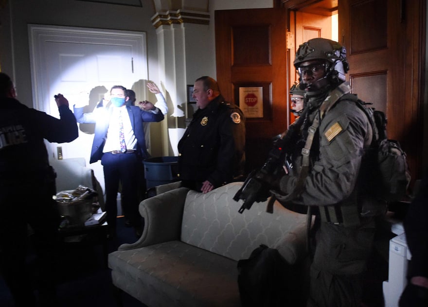 Congress staffers hold up their hands while Capitol Police Swat teams check everyone in the room as they secure the floor of Trump suporters in Washington, DC on January 6, 2021.