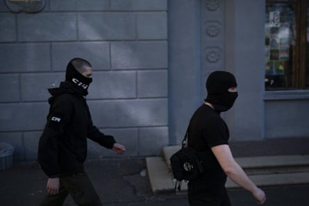 Members of a far right group, some of them wearing balaclavas, march toward a Russian orthodox church in Kiev
