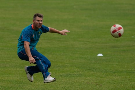 Australia’s David Warner kicks a round football at training.