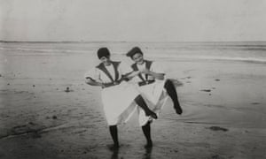 Two girls standing together on beach, each with their left foot raised, circa 1897