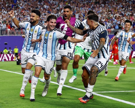 Argentina players in white and blue striped jerseys celebrate together on a pitch