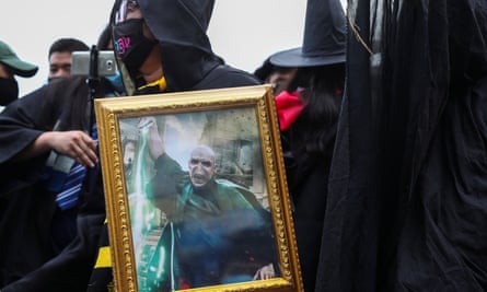 A pro-democracy protester dressed as a wizard holds up a picture of Lord Voldemort.