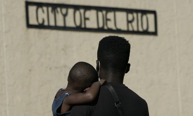 A Haitian migrant carries a boy while waiting to board a bus provided by a humanitarian group after being released from US custody in Del Rio, Texas.
