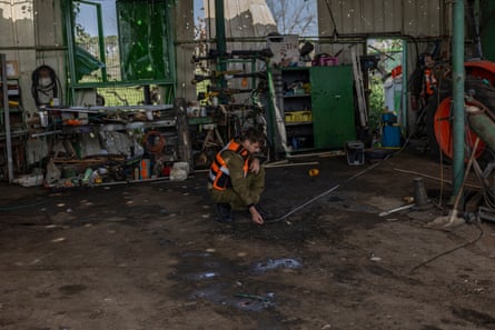 A person in a hi-vis gilet crouches in a damaged building