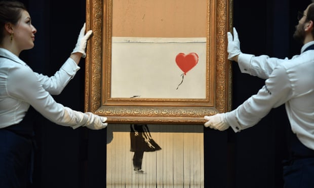 Sotheby’s employees pose with Banksy’s Love is in the Bin, which was created when the painting Girl With Balloon was passed through a shredder in London in October 2018
