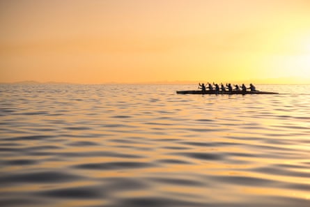 Eight people paddle in unison at dawn
