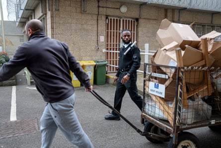 Chibs Ekeiwu looks at a man pulling a trolley full of cardboard boxes