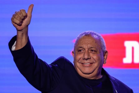 Gadi Eisenkot gives a thumbs-up with a bright screen behind him