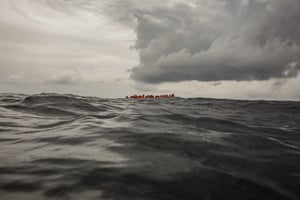 Refugees and migrants wait to be rescued by aid workers of the Spanish NGO Proactiva Open Arms, after leaving Libya aboard an overcrowded rubber boat.