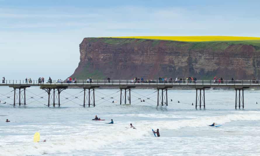 Surfers wait for a wave next to Saltburn’s Victorian pier.