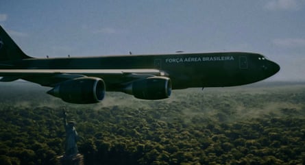 A Brazilian air force plane flying over a replica of the Statue of Liberty in the jungle
