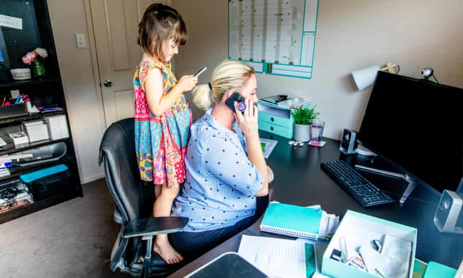 Middle Aged Woman working from home in office whilst also looking after her young daughter