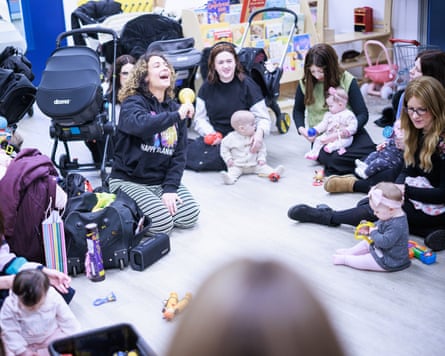 Women and babies sitting on floor and talking with prams behind them