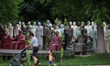 Dozens of statues by a park path, will father and toddler walking