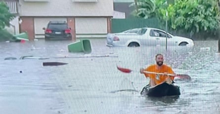 Man kayaking through flooded streets
