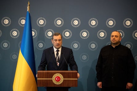 Vadym Skibitskyi speaking at a podium in front of a Ukraine flag next to Rustem Umerov