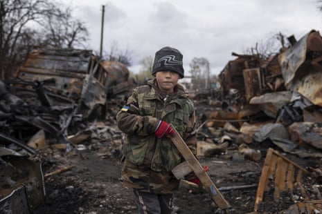 Yehor, seven, holds a toy rifle next to destroyed Russian military vehicles near Chernihiv, Ukraine.