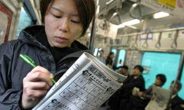 A commuter in Japan completing sudoku puzzles on a train
