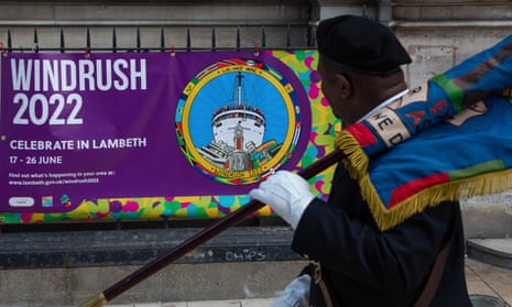 A West Indian Association Service Personnel walks past a banner saying "Windrush 2022" in Windrush square.