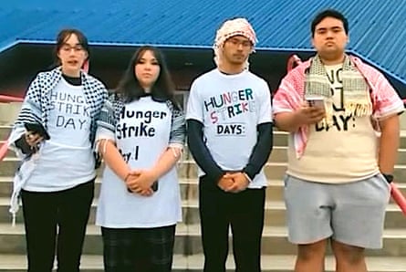 four people wearing shirts saying ‘hunger strike day 1’ stand outside