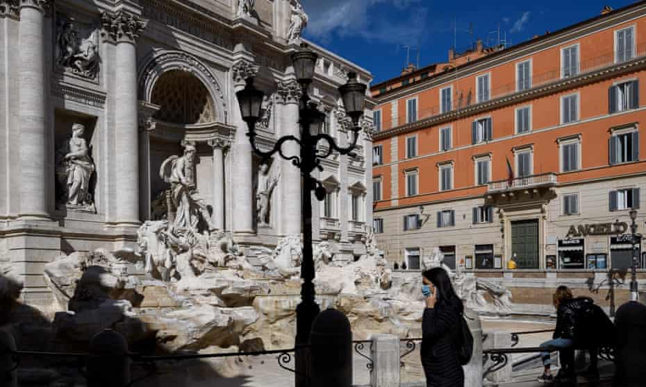 A woman wearing a face mask walks around the Trevi fountain in Rome, Italy, empty and without tourists, in March.
