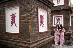 Two women check their smartphones at Tran Quoc pagoda in Hanoi, Vietnam