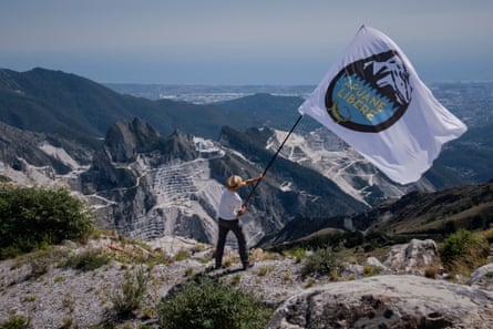 A volunteer from Apuane Libere waves the group’s flags above a quarry in Carrara, Italy