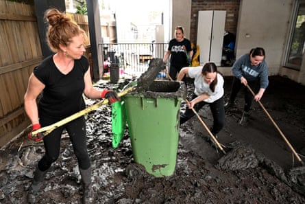 People clear mud from a property damaged by floods in the Melbourne suburb of Maribyrnong on 15 October.