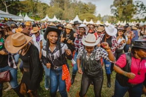 A large group of people, many wearing cowboy and cowgirl attire line-dance