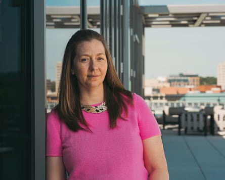Katherine D’Zmura on a balcony and wearing a pink short-sleeves knitted top