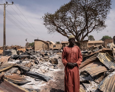 A resident stands among burnt debris and damaged homes after the attack in Woro, Kwara state
