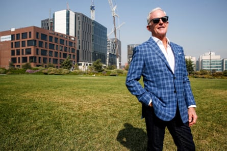 A man poses for a photograph on grass in front of new buildings