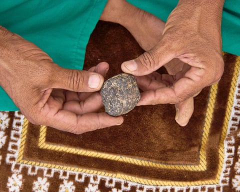 Lamine Ould Hanoun inspecting a small grey and white rock