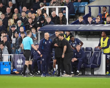 The match referee, Edward Duckworth, speaks to both managers during the break in play.