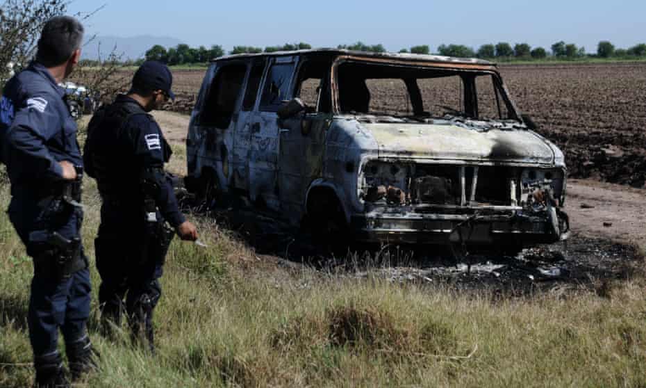 police investigate a burned out van in Mexico.