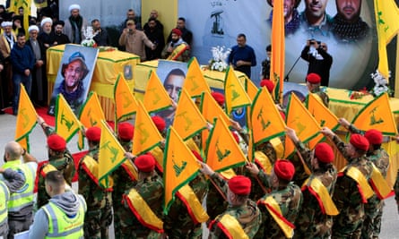 Hezbollah militants holding flags stand near the coffins of comrades
