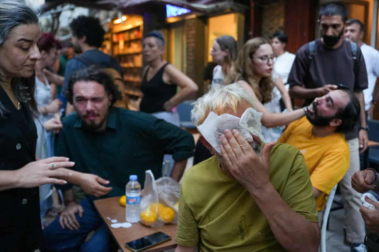 People help treat others with red faces and streaming eyes from teargas