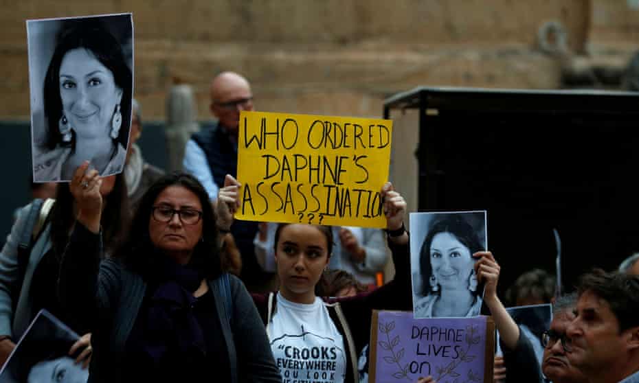 People hold up posters and pictures of anti-corruption journalist Daphne Caruana Galizia during a vigil and demonstration in May.
