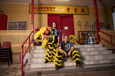 Team instructor Jenny Cao and Long Huynh sit on stairs outside the hall at the Mingyue Lay temple. The pair are wearing the fluffy yellow and black striped pants of the lion costume
